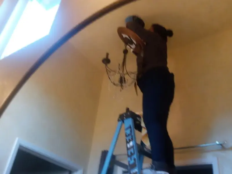 Electrician installing a chandelier in a Spring Valley residence